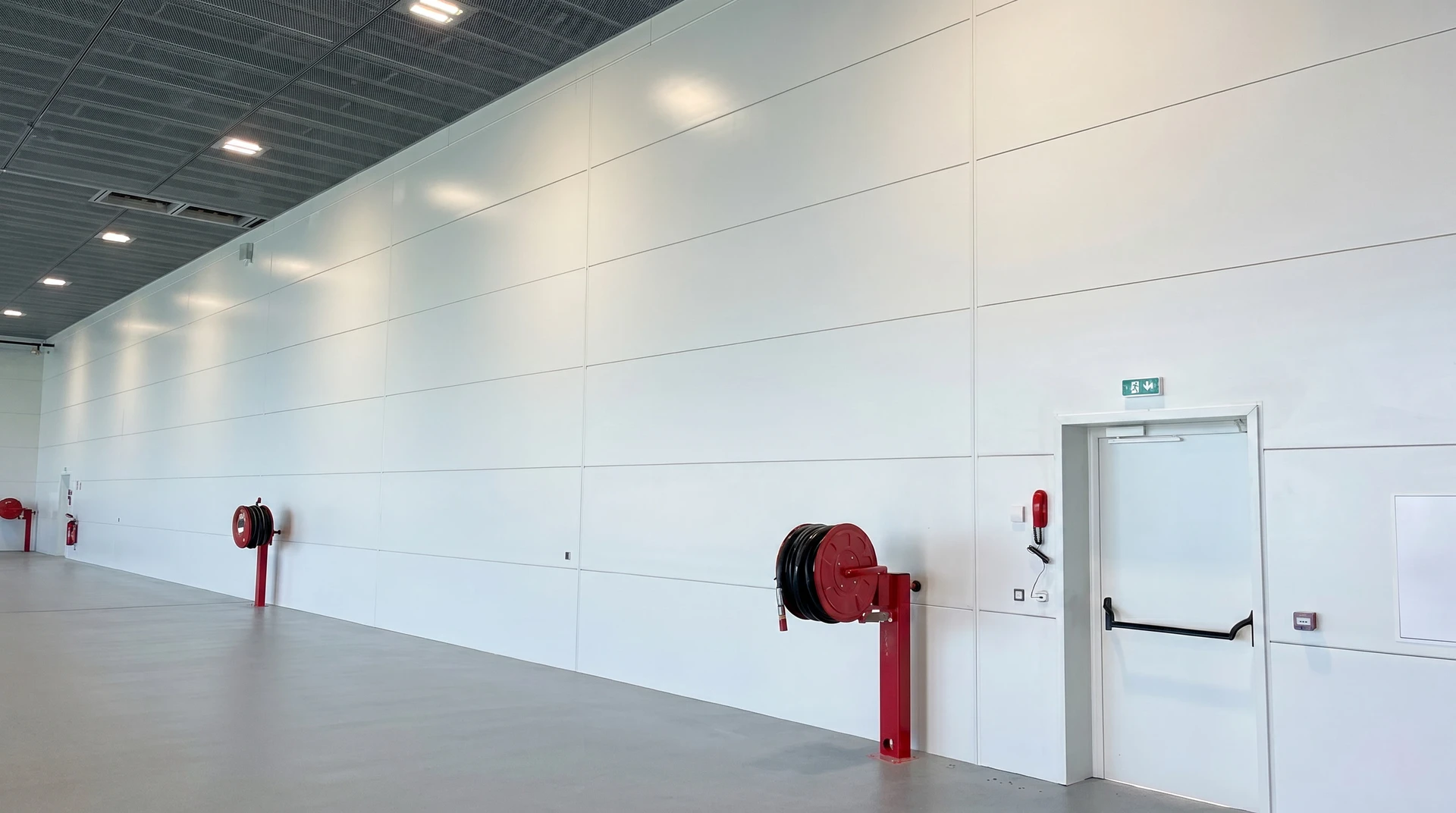 Vue aérienne d'un complexe industriel moderne avec bâtiments de production à toitures plates, zones de stockage extérieures et parkings