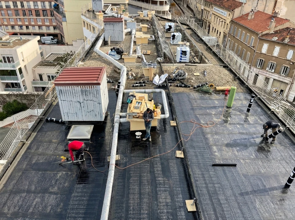 Terrasse en béton sur toit d'immeuble urbain avec garde-corps en béton, située entre tours résidentielles modernes