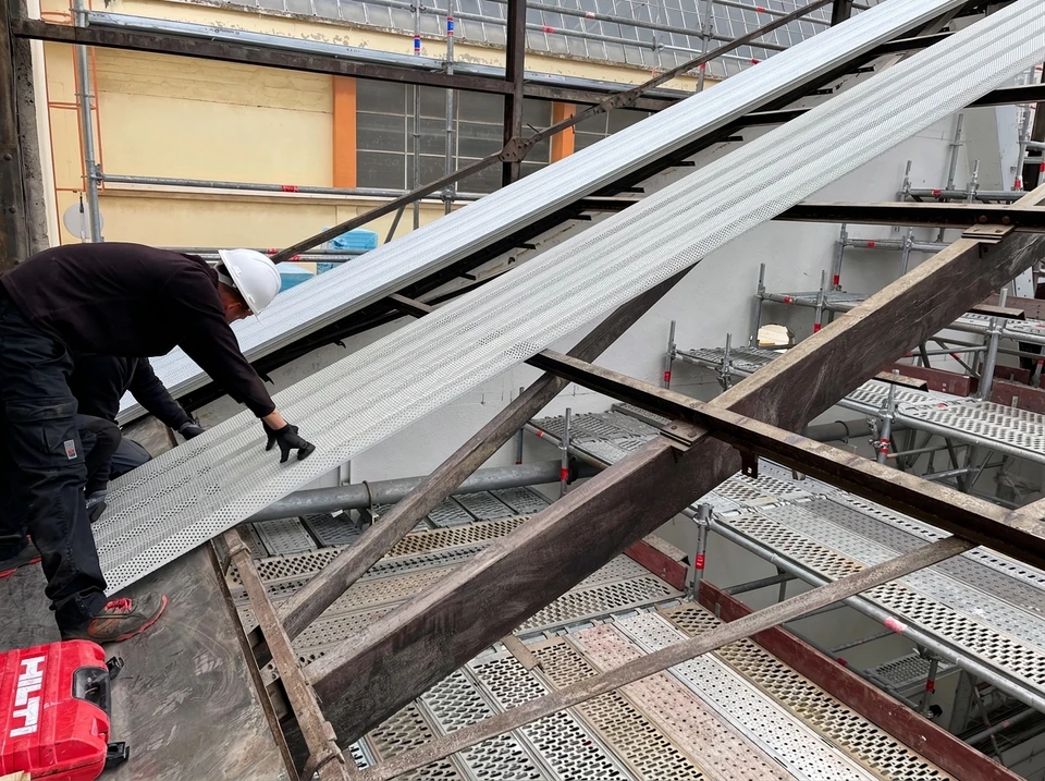 Ouvrier en équipement de protection installant une structure métallique sur une toiture membrane étanche